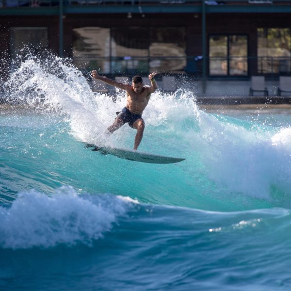 image of a adult male taking a advanced surf session riding a wave with a surfboard at waco surf a texas water park