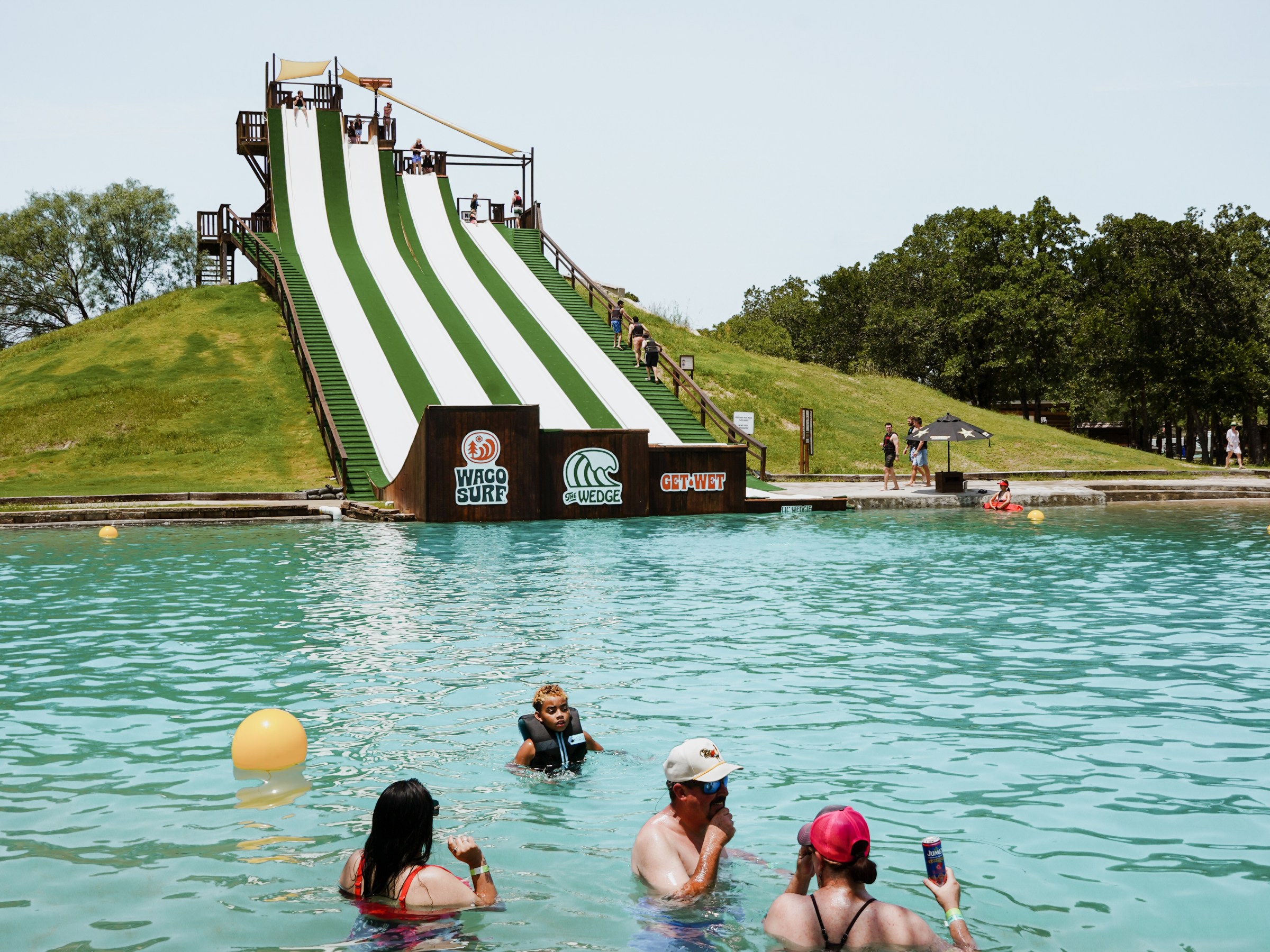 People swimming near a large water slide with multiple lanes at a park.