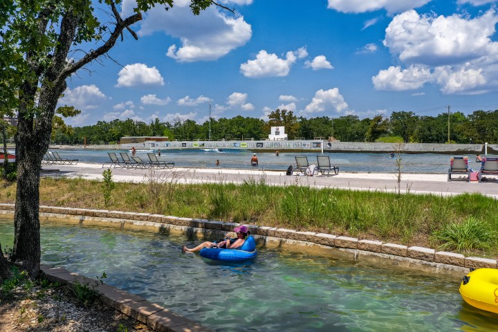 Women relaxing on the lazy river with the surf lagoon in the background