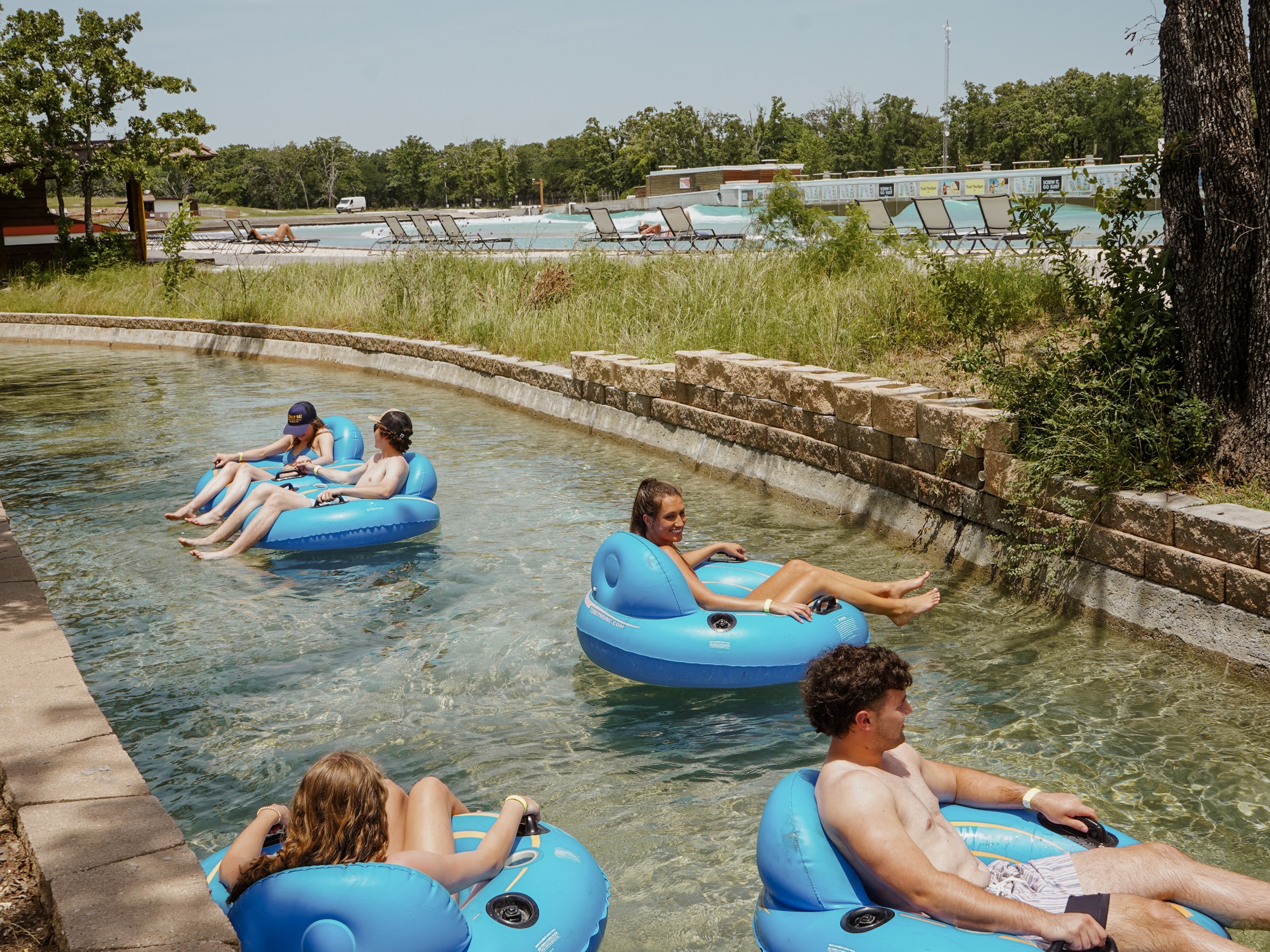 Group of people floating on blue tubes in a lazy river at a water park.